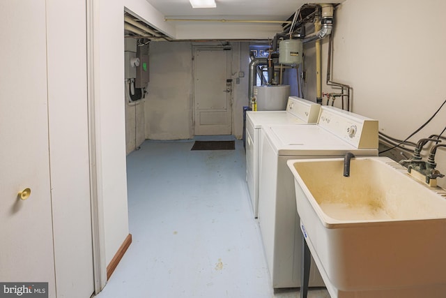 clothes washing area featuring sink, gas water heater, and washer and clothes dryer