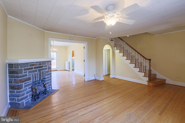 unfurnished living room featuring crown molding, ceiling fan, light wood-type flooring, and a fireplace