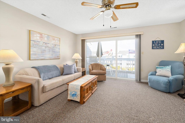 carpeted living room with ceiling fan and a textured ceiling