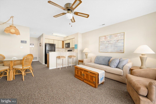 living room featuring ceiling fan, dark carpet, and a textured ceiling