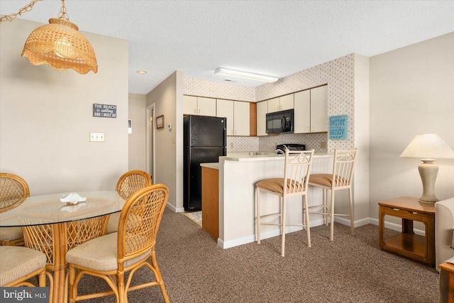 kitchen featuring pendant lighting, black appliances, light colored carpet, kitchen peninsula, and a textured ceiling