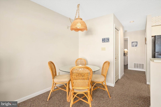 dining area with carpet and a textured ceiling