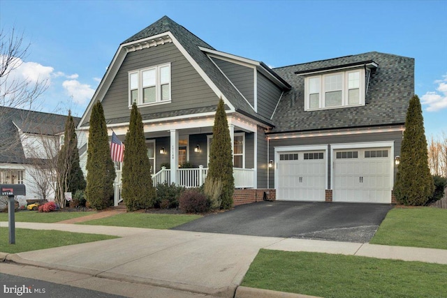 view of front of property with a porch, a garage, and a front lawn