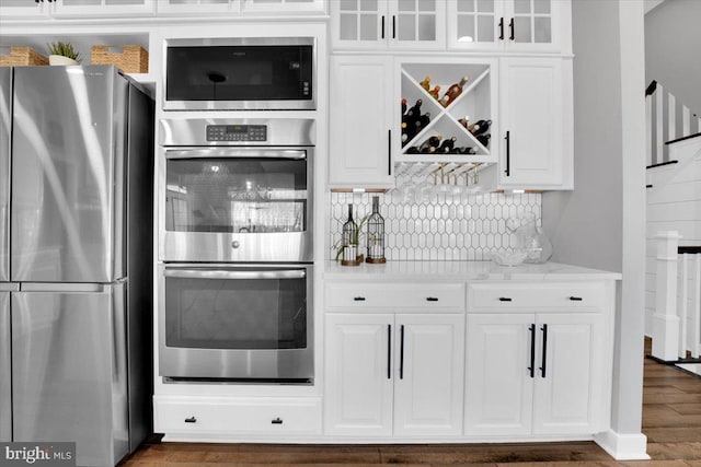 kitchen featuring stainless steel appliances, white cabinetry, and backsplash