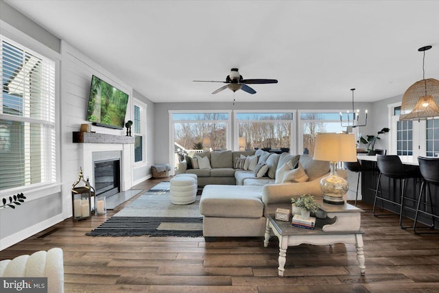 living room featuring dark hardwood / wood-style flooring and ceiling fan with notable chandelier