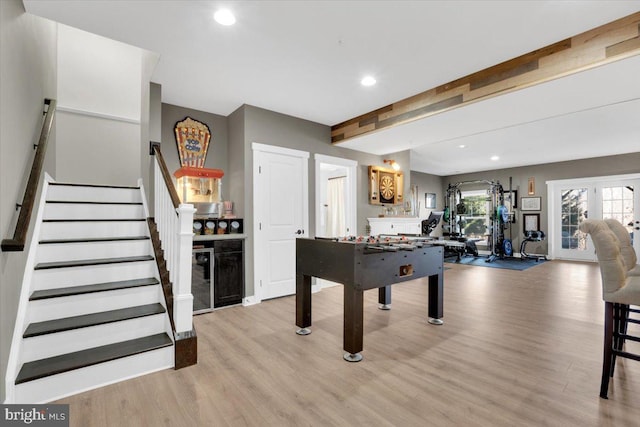 game room featuring french doors, beamed ceiling, and light wood-type flooring