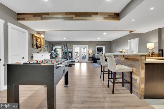 game room with bar and light wood-type flooring