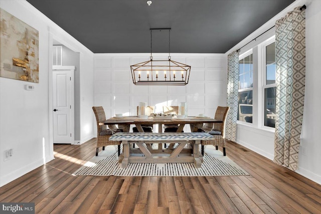 dining area with a notable chandelier, wood-type flooring, and ornamental molding