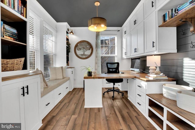 office space featuring dark wood-type flooring, plenty of natural light, and built in desk