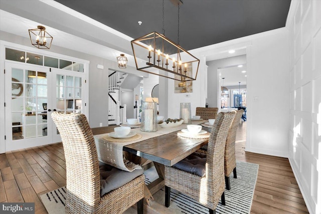 dining area featuring wood-type flooring, an inviting chandelier, and french doors