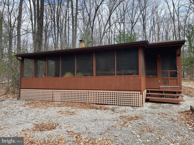 view of home's exterior featuring a sunroom and a chimney