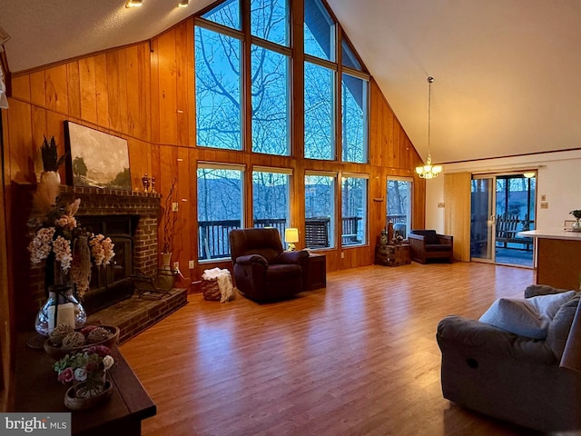 living room with hardwood / wood-style floors, a fireplace, wooden walls, and a chandelier