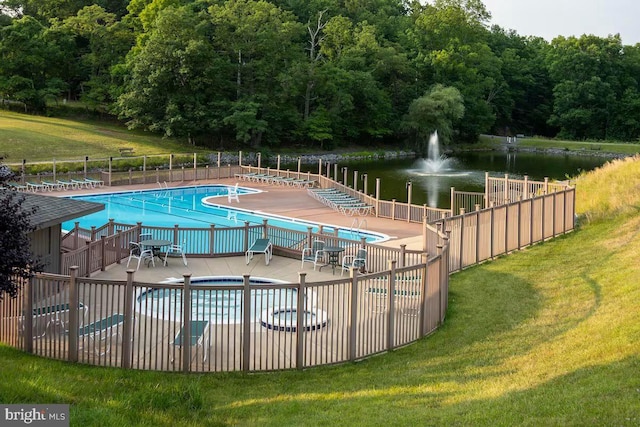 view of swimming pool featuring a water view and a lawn