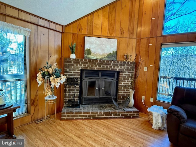 living room with lofted ceiling, light wood-type flooring, a textured ceiling, and wood walls