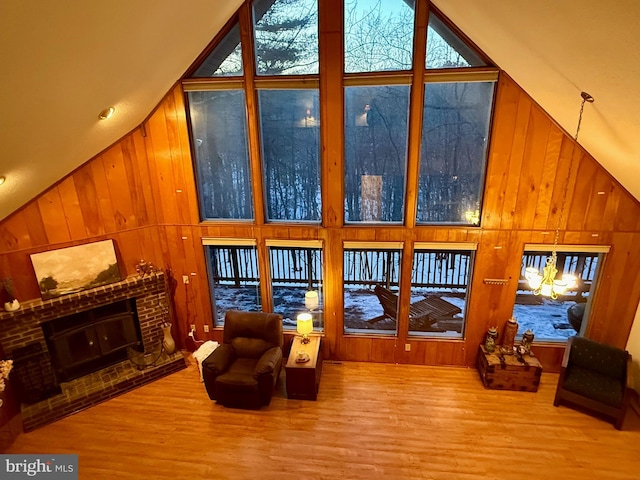 living room with a brick fireplace, wooden walls, and high vaulted ceiling