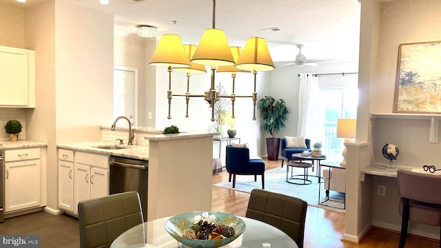 interior space with pendant lighting, white cabinets, sink, and dishwasher