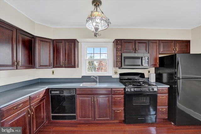 kitchen with hanging light fixtures, dark hardwood / wood-style floors, black appliances, and sink