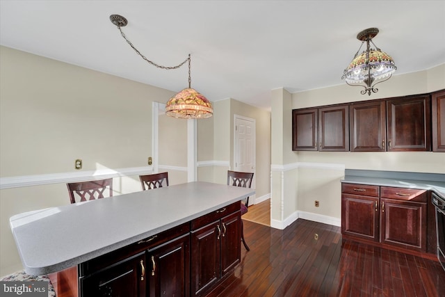 kitchen with a breakfast bar area, dark hardwood / wood-style flooring, and decorative light fixtures