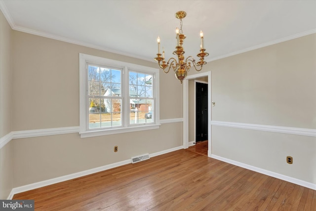 unfurnished dining area featuring hardwood / wood-style floors, crown molding, and a chandelier