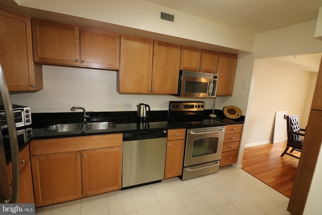 kitchen featuring stainless steel appliances, sink, a textured ceiling, and light hardwood / wood-style flooring