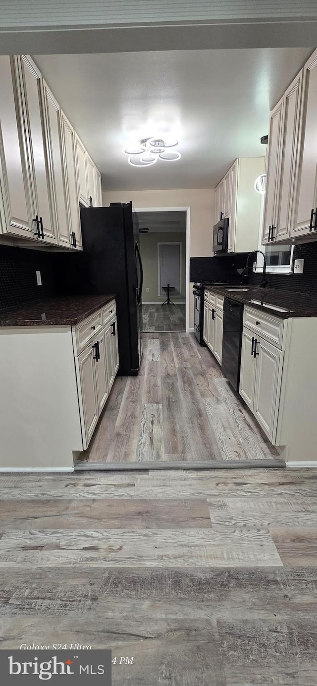 kitchen featuring white cabinets, sink, light wood-type flooring, and black appliances