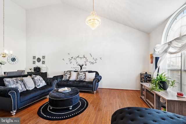 living room with high vaulted ceiling, a notable chandelier, and wood finished floors