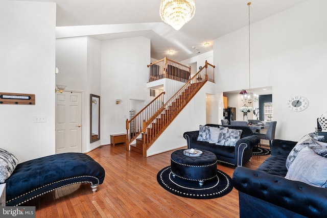 living room featuring stairs, high vaulted ceiling, a notable chandelier, and wood finished floors