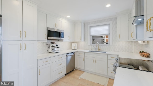 kitchen featuring sink, light hardwood / wood-style flooring, appliances with stainless steel finishes, white cabinets, and decorative backsplash