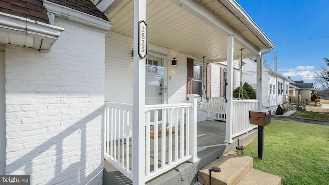 doorway to property with a lawn and a porch