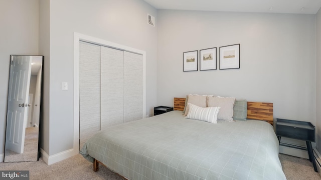 bedroom featuring a baseboard heating unit, light colored carpet, and a closet