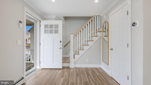 foyer entrance featuring baseboard heating, ornamental molding, and light wood-type flooring