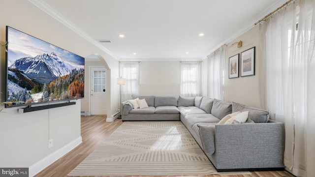 living room featuring a baseboard heating unit, crown molding, and light wood-type flooring