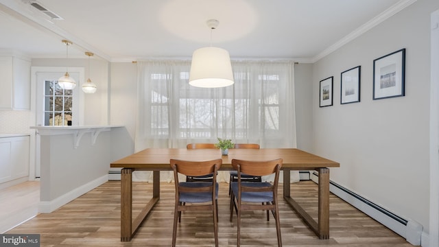 dining space with baseboard heating, crown molding, and light hardwood / wood-style floors