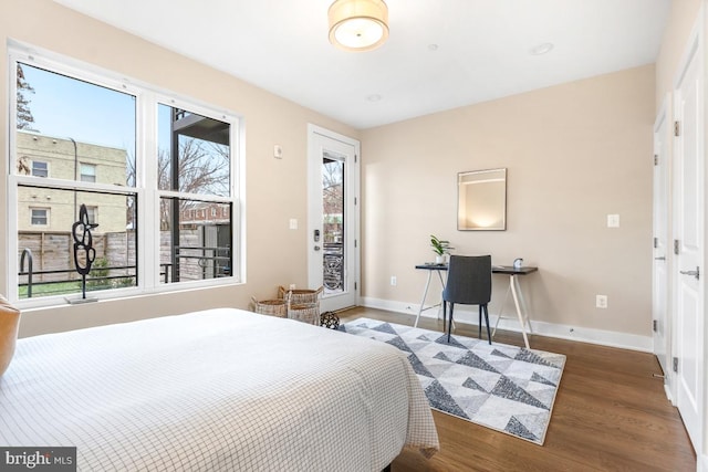 bedroom with multiple windows, dark hardwood / wood-style floors, and access to outside