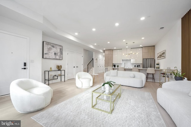 living room with an inviting chandelier and light hardwood / wood-style flooring