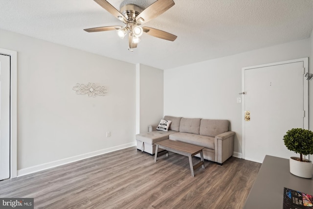 living room with ceiling fan, dark hardwood / wood-style flooring, and a textured ceiling