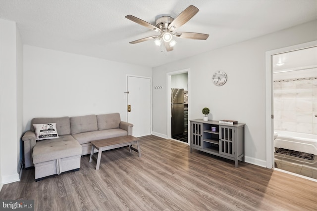 living room featuring a textured ceiling, wood-type flooring, and ceiling fan