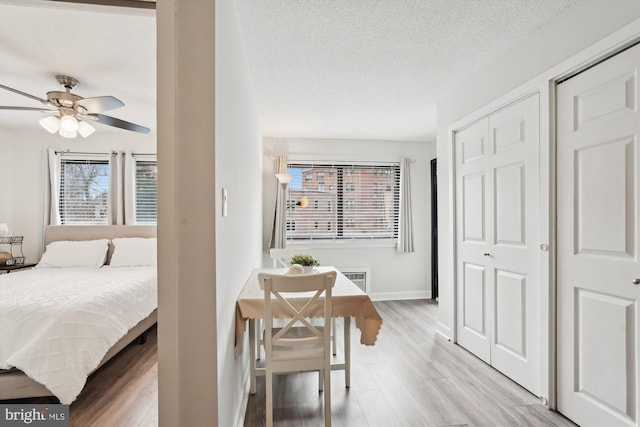 bedroom featuring ceiling fan, a textured ceiling, and light hardwood / wood-style floors