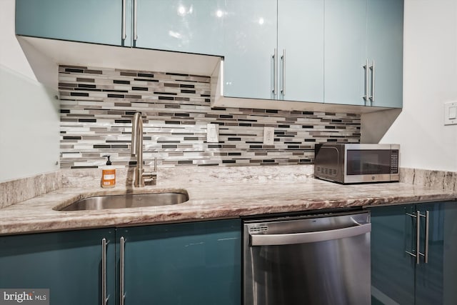 kitchen with tasteful backsplash, appliances with stainless steel finishes, blue cabinets, and sink