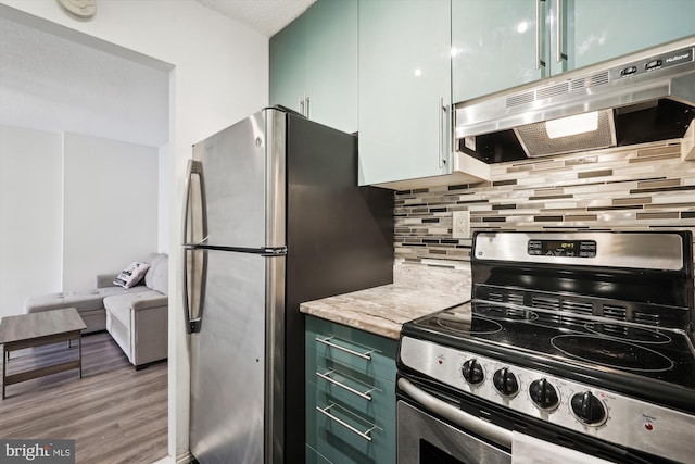 kitchen with hardwood / wood-style flooring, appliances with stainless steel finishes, green cabinetry, and decorative backsplash