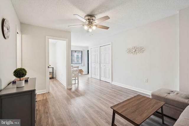 living room featuring ceiling fan, hardwood / wood-style floors, and a textured ceiling