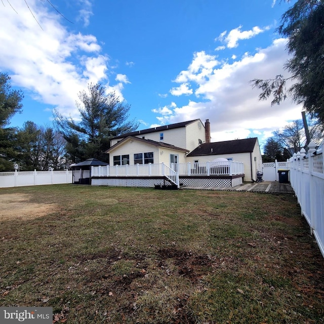 rear view of house featuring a wooden deck and a lawn