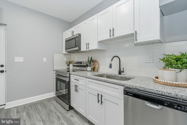 kitchen featuring light stone counters, stainless steel appliances, sink, and white cabinets