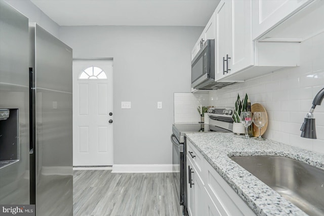 kitchen featuring white cabinetry, sink, light stone counters, and stainless steel appliances