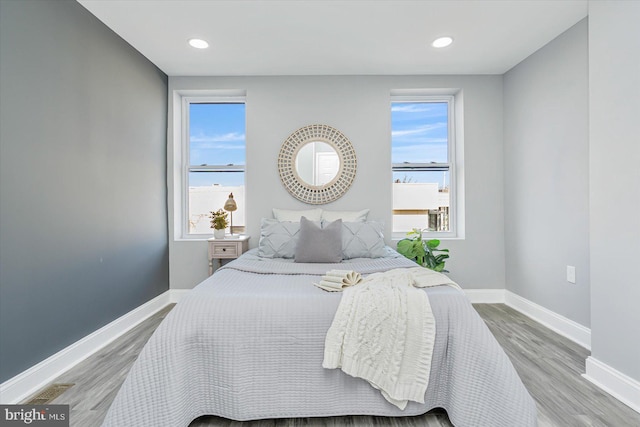 bedroom featuring a water view and hardwood / wood-style floors