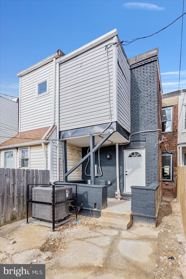 rear view of property with central AC unit and a garage