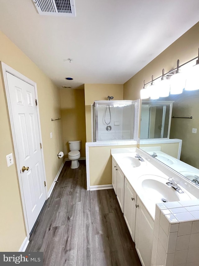 bathroom with an enclosed shower, hardwood / wood-style floors, vanity, and toilet