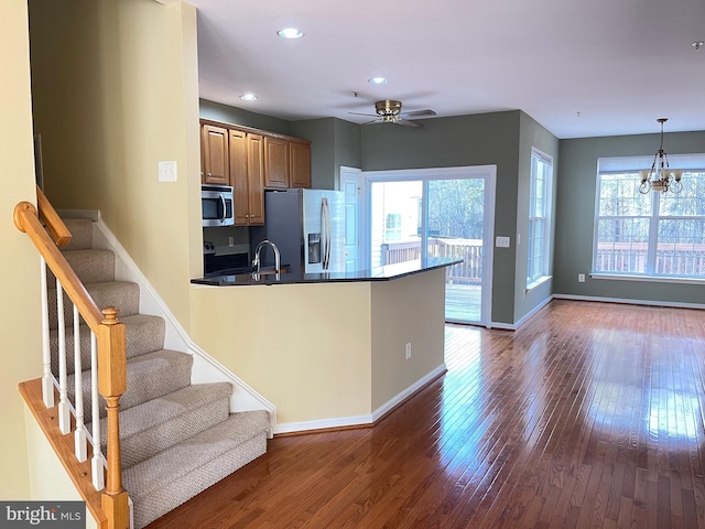 kitchen featuring appliances with stainless steel finishes, ceiling fan with notable chandelier, sink, hanging light fixtures, and dark wood-type flooring