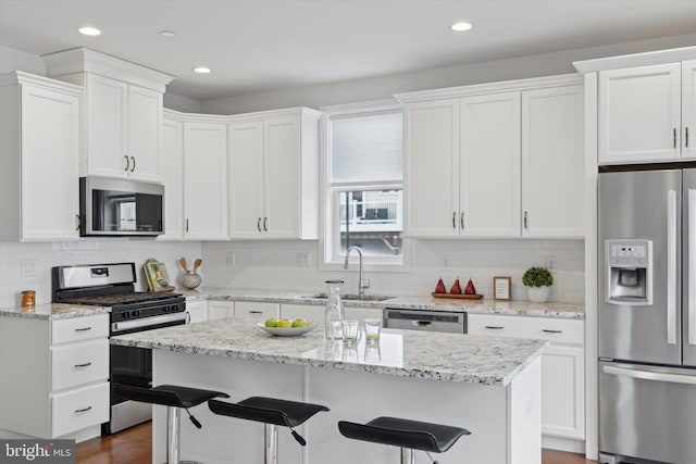 kitchen featuring white cabinetry, stainless steel appliances, a center island, and sink