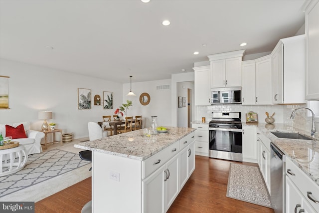 kitchen featuring sink, decorative light fixtures, a center island, appliances with stainless steel finishes, and white cabinets